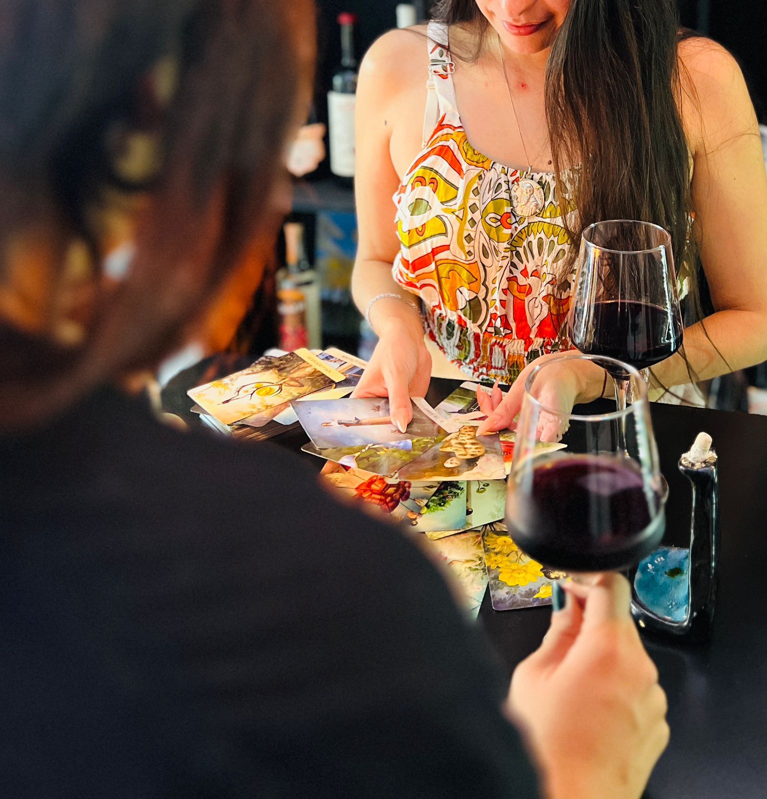 Gisel realizando una lectura de cartas en una mesa con copas de vino